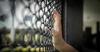Hand gripping a fence.