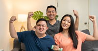 Autistic young adult male and parents raising fists with smiles.
