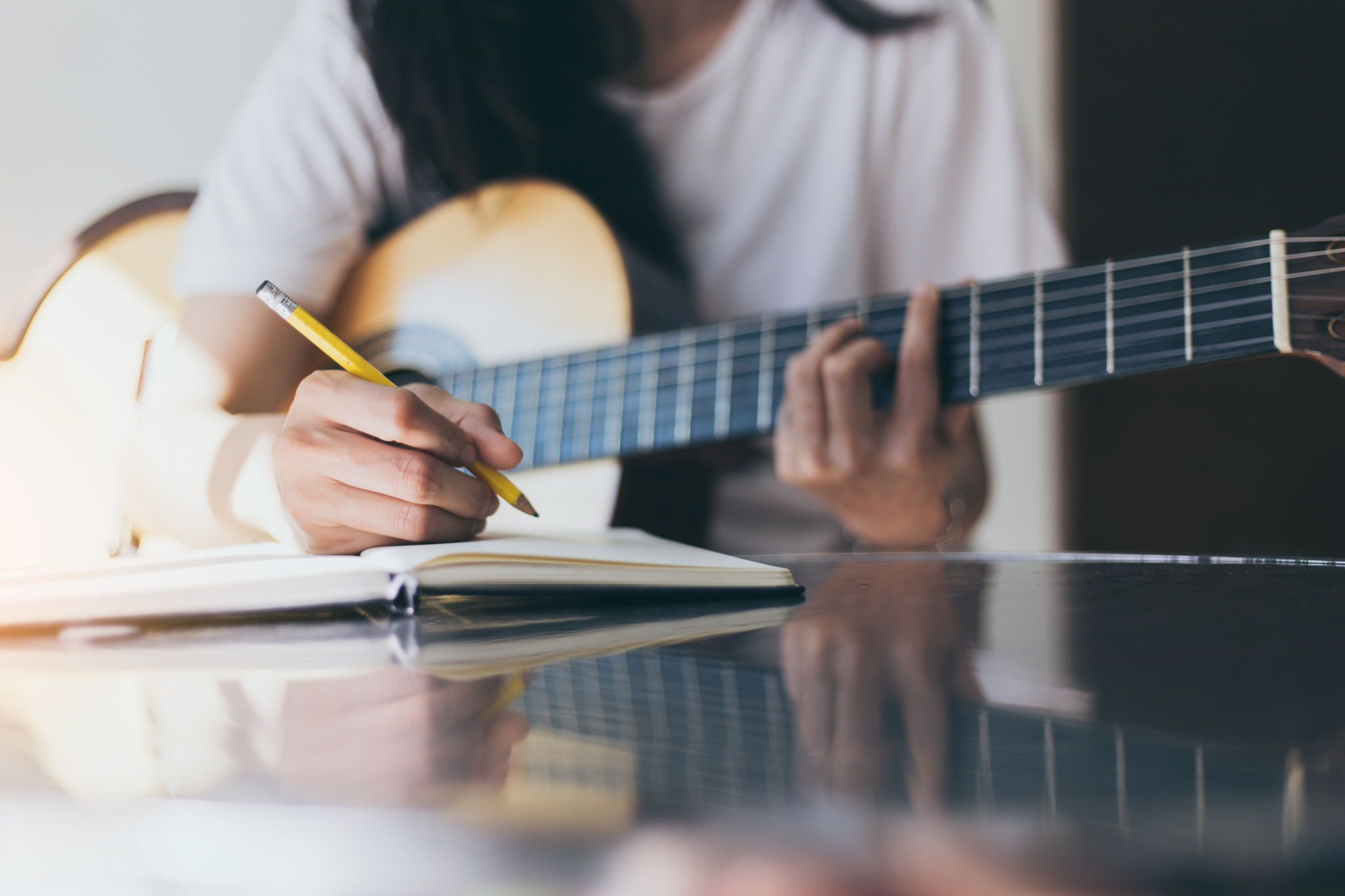A songwriter thinking while writing notes and lyrics in a book