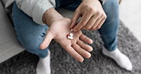 A man's hand, holding opioid pills