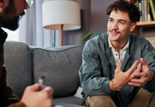 A therapist and a man are discussing mental health advice or support in an office.