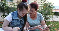 Two women sitting next to each other, both holding their smart phones.