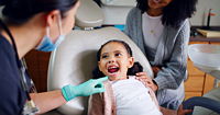 Child with their mouth open in a consultation with dentist in office for dental checkup.