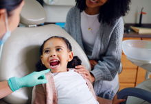 Child with their mouth open in a consultation with dentist in office for dental checkup.