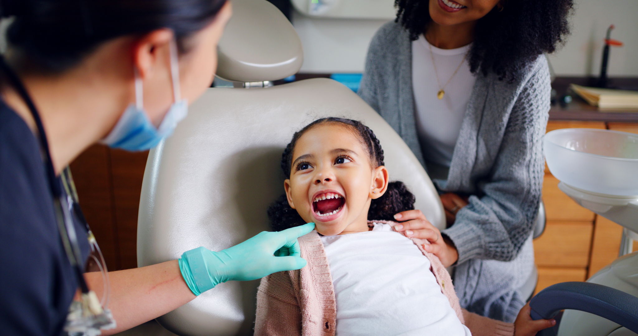 Child with their mouth open in a consultation with dentist in office for dental checkup.