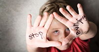A child raising their hands up with "stop bullying" written on the palms.