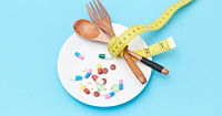 A blue back drop with a plate containing an assortment of pills and a wooden fork and spoon with a yellow measuring tape wrapped around them.