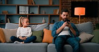 A child in need of attention is ignored by their phone addicted parent.