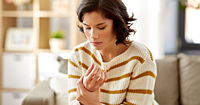 Young woman suffering from pain in hand at home