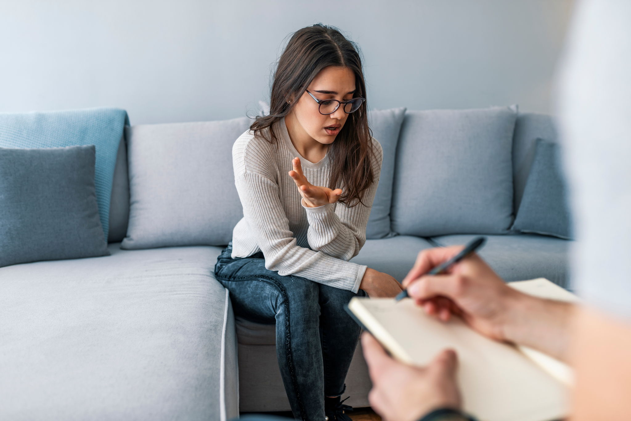 Psychologist listening to woman in trouble during therapy session.