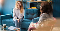 Happy red-haired woman talking to a female psychologist. Discusses her problems, mental trauma.