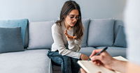 Psychologist listening to woman in trouble during therapy session.