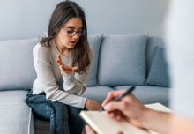 Psychologist listening to woman in trouble during therapy session.