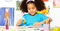A young girl playing at a table with craft supplies