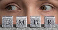 A close up of two hazel eyes looking to the side with grey blocks in front of them with letters forming "EMDR"