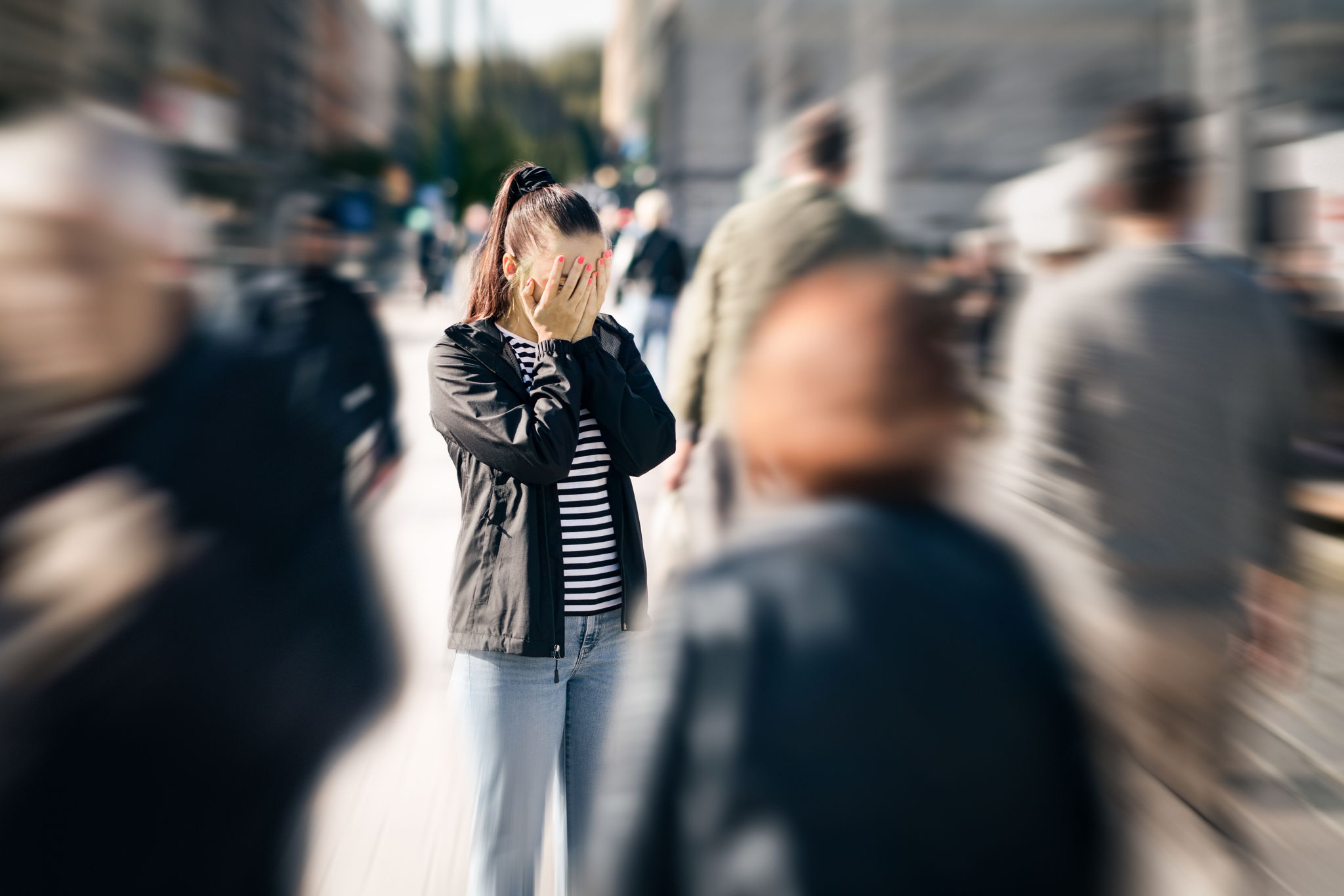 An anxious woman in a crowd of people in street