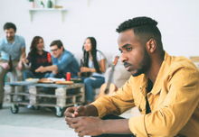 Young man feels upset and isolated while his friends drink and party