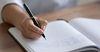 Close up of person's hand, writing in their journal