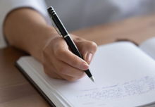 Close up of person's hand, writing in their journal